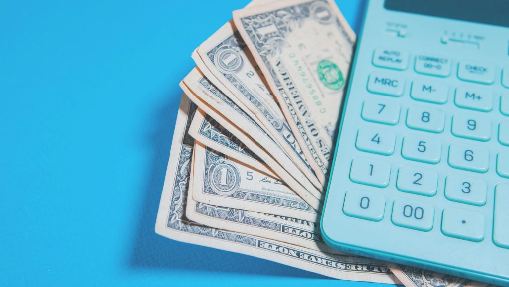 Us dollar bills and a calculator on blue background