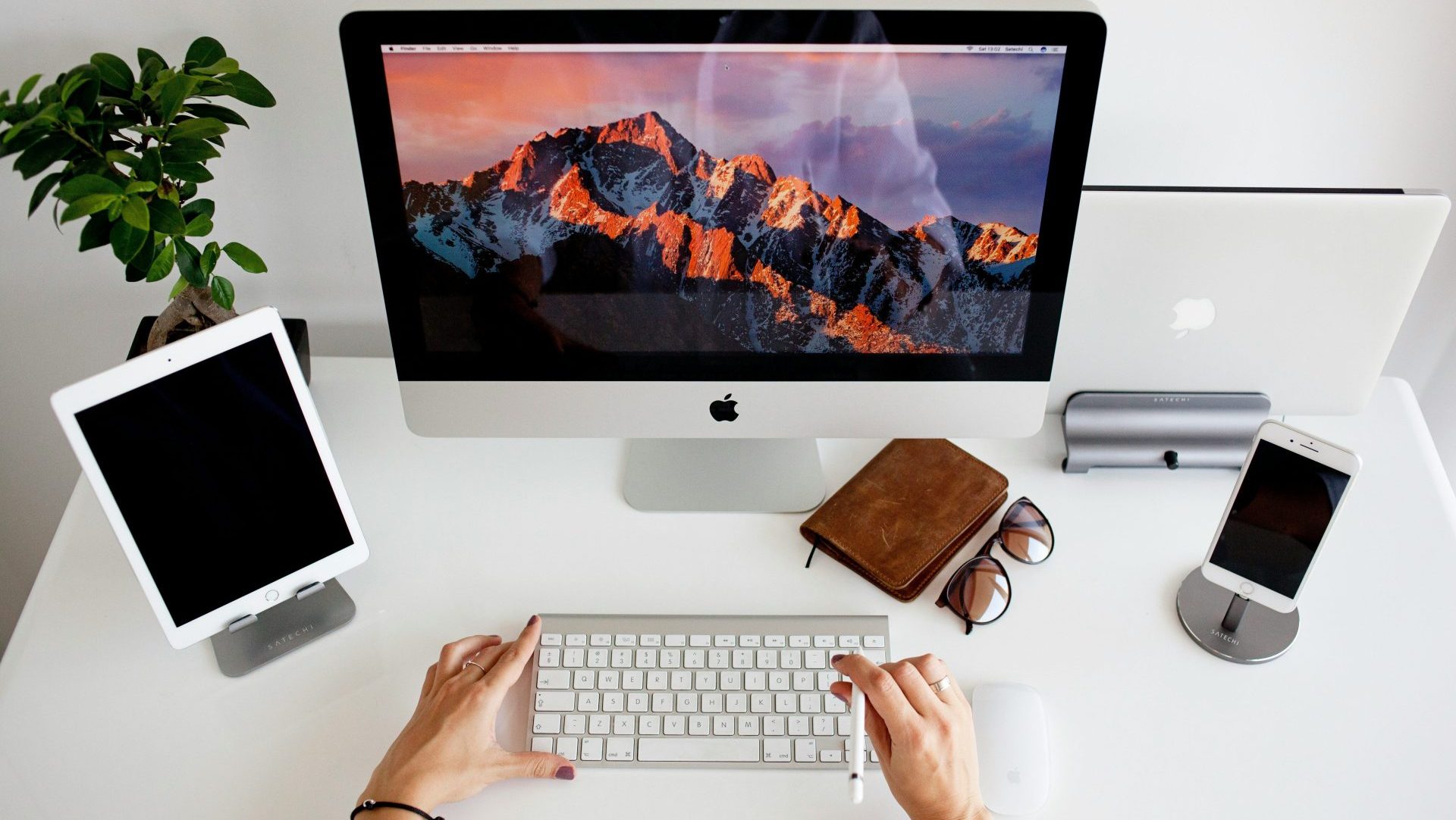 person using silver imac and apple magic keyboard